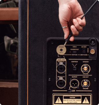 Close-up of the Spark CAB 2 rear panel: Spark input, XLR/TRS combo inputs, XLR output and volume controls, with a hand plugging in a cable