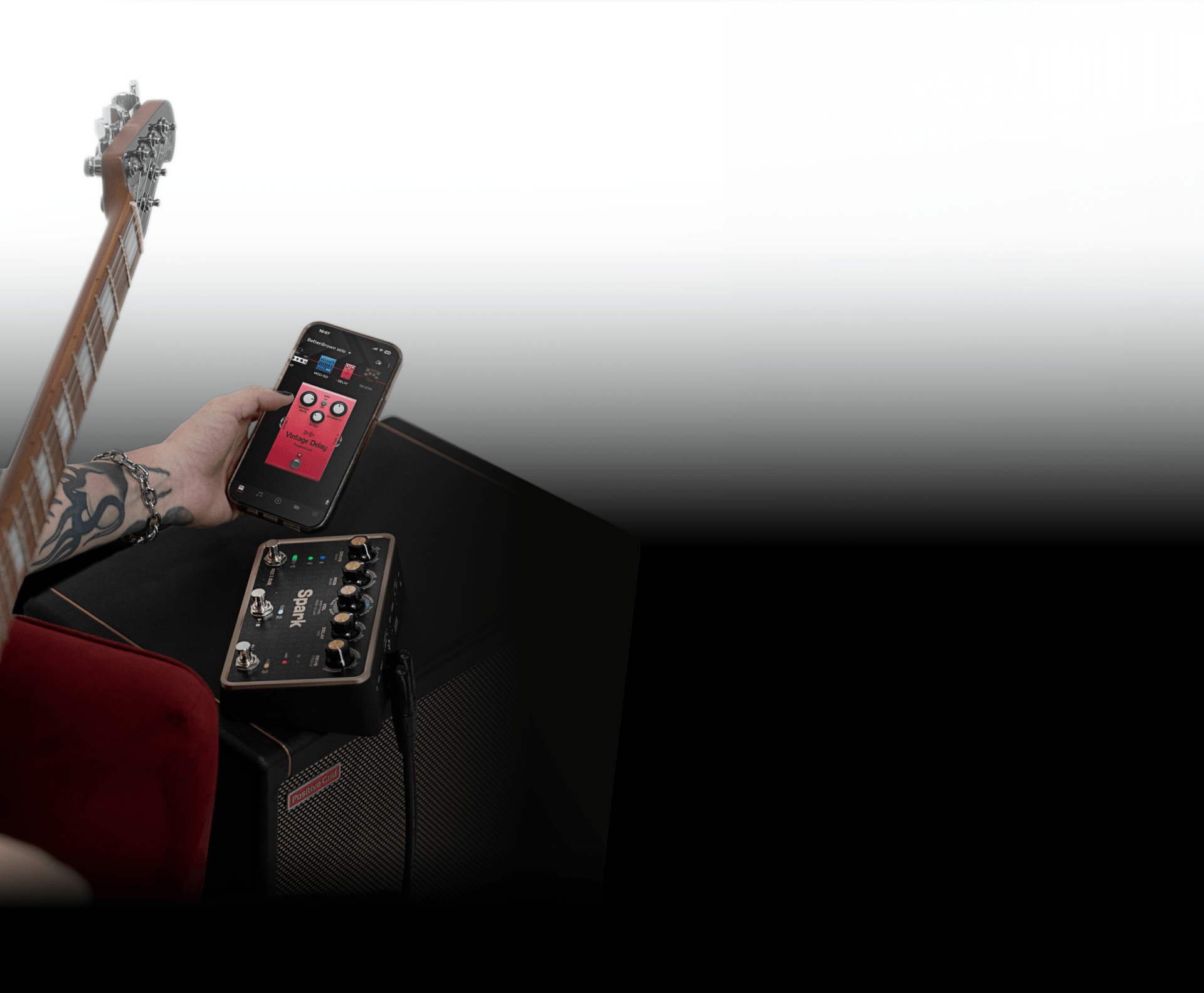 Guitarist tapping a tone on the Spark app, with Spark PEDAL and amp in the background