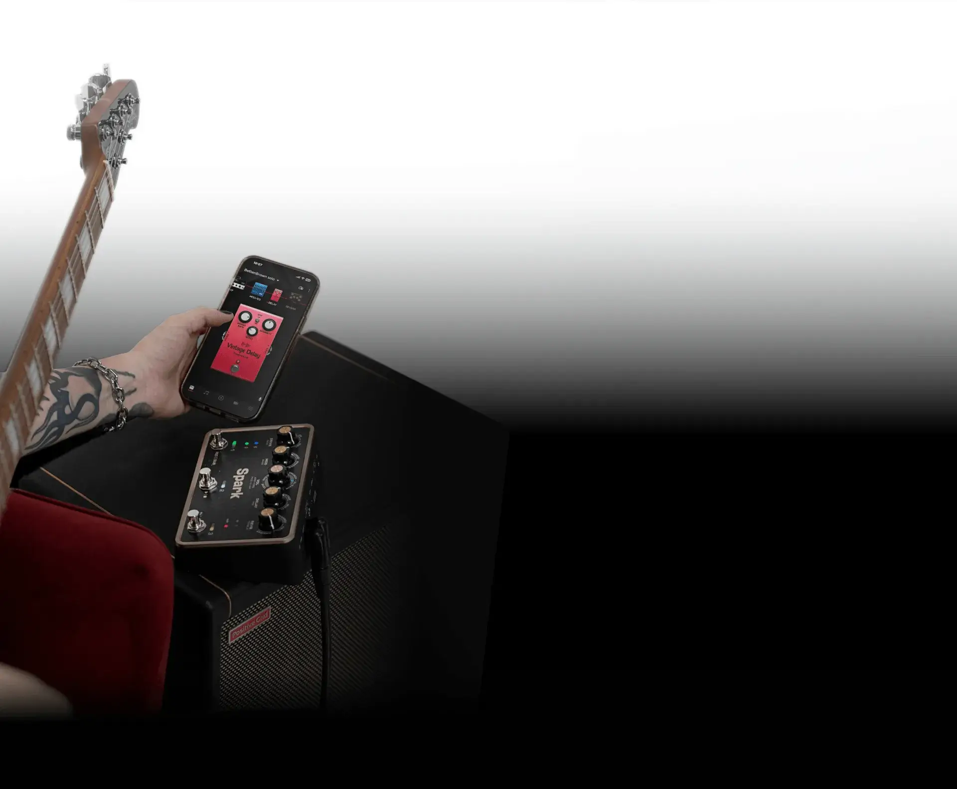 Guitarist tapping a tone on the Spark app, with Spark PEDAL and amp in the background