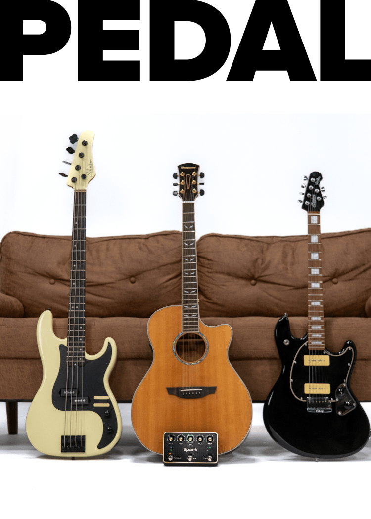 Bass, acoustic, and electric guitars leaning against a couch in front of giant PEDAL lettering, with a Spark PEDAL on the floor